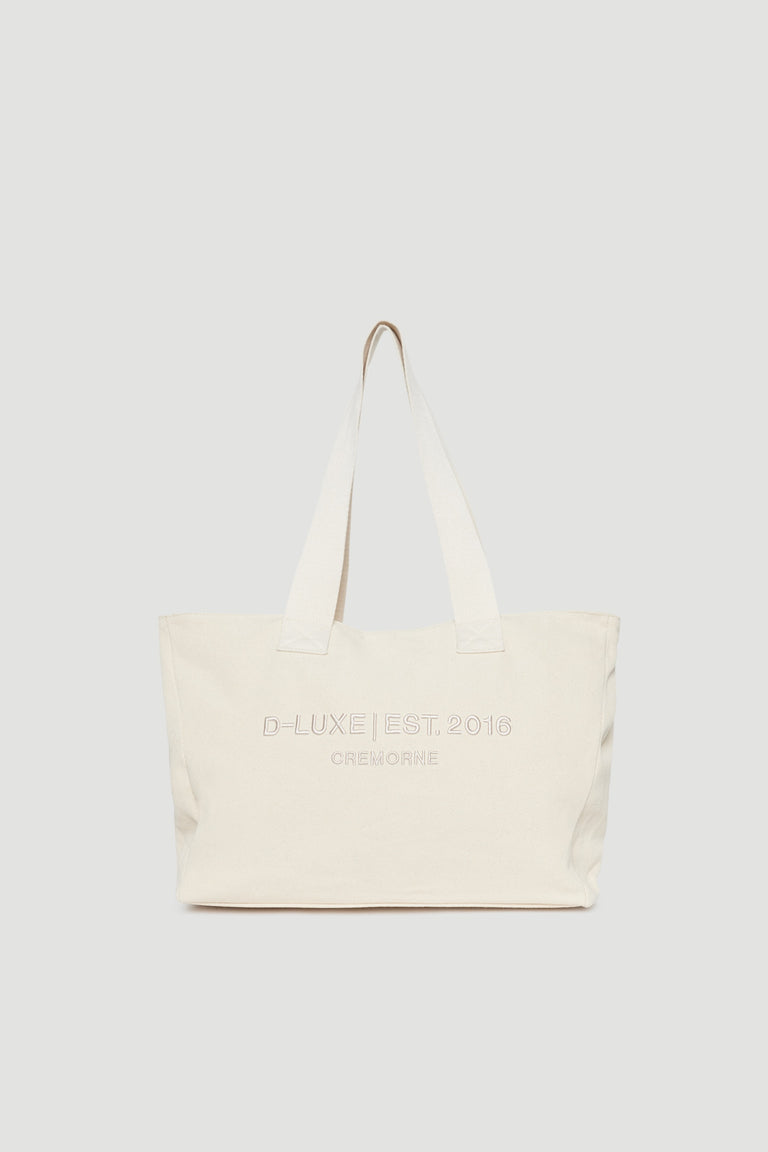 Structured cream tote bag with wide shoulder straps and subtle front logo embroidery detail