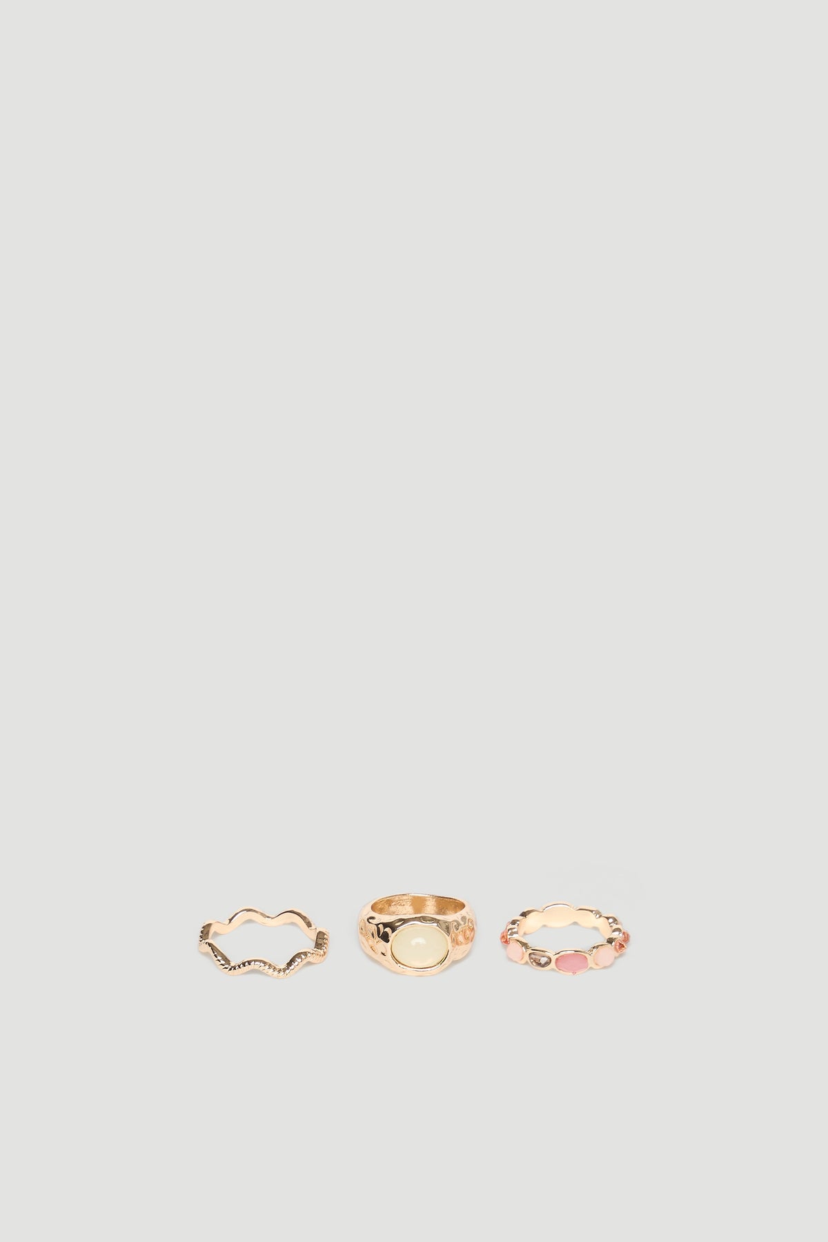 Set of three delicate gold rings featuring textured and stone-accented designs for a versatile, elegant look.