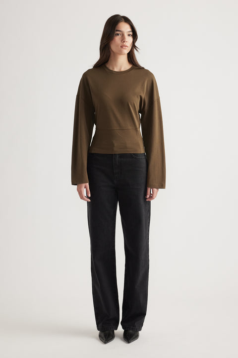 Woman wearing an olive long sleeve fitted top paired with high-waisted black straight-leg jeans and pointed black boots