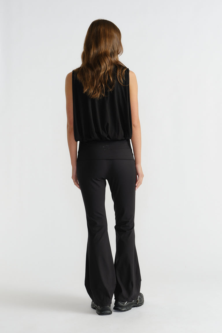 Back view of woman wearing a relaxed-fit black sleeveless bubble tank paired with flared black pants and sneakers
