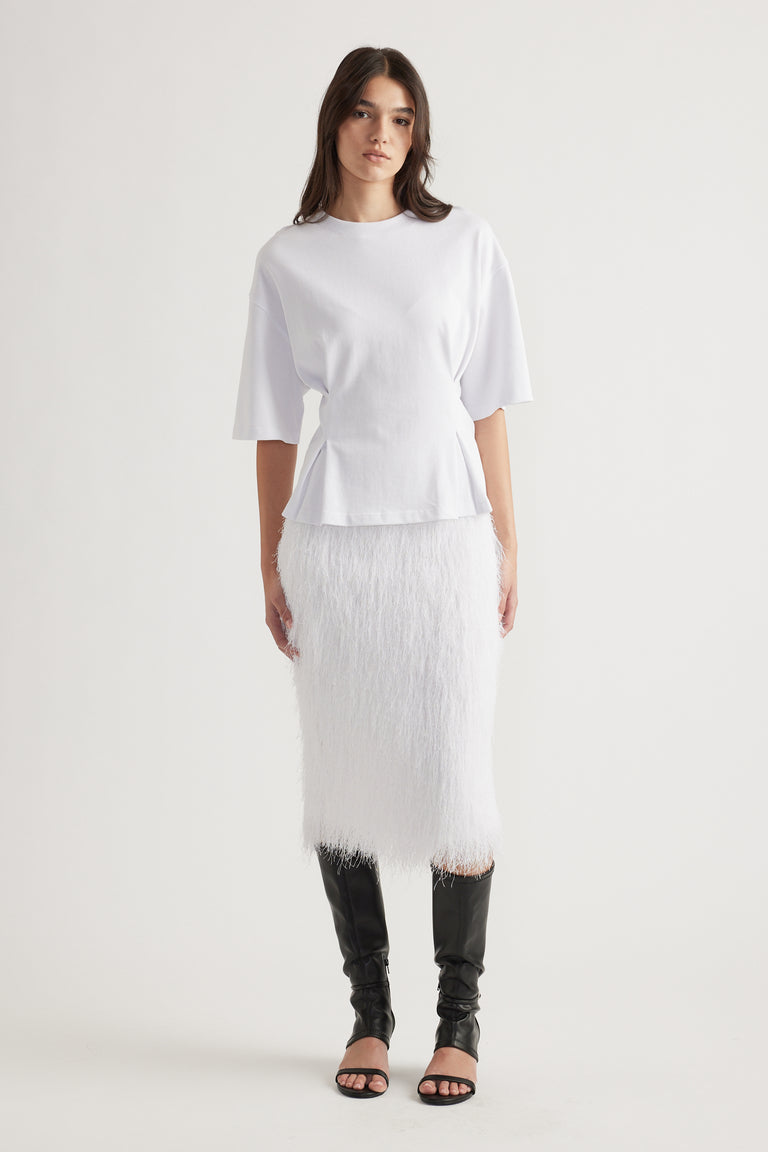 Woman wearing a white structured tee with elbow-length sleeves and a textured midi skirt paired with black heeled boots