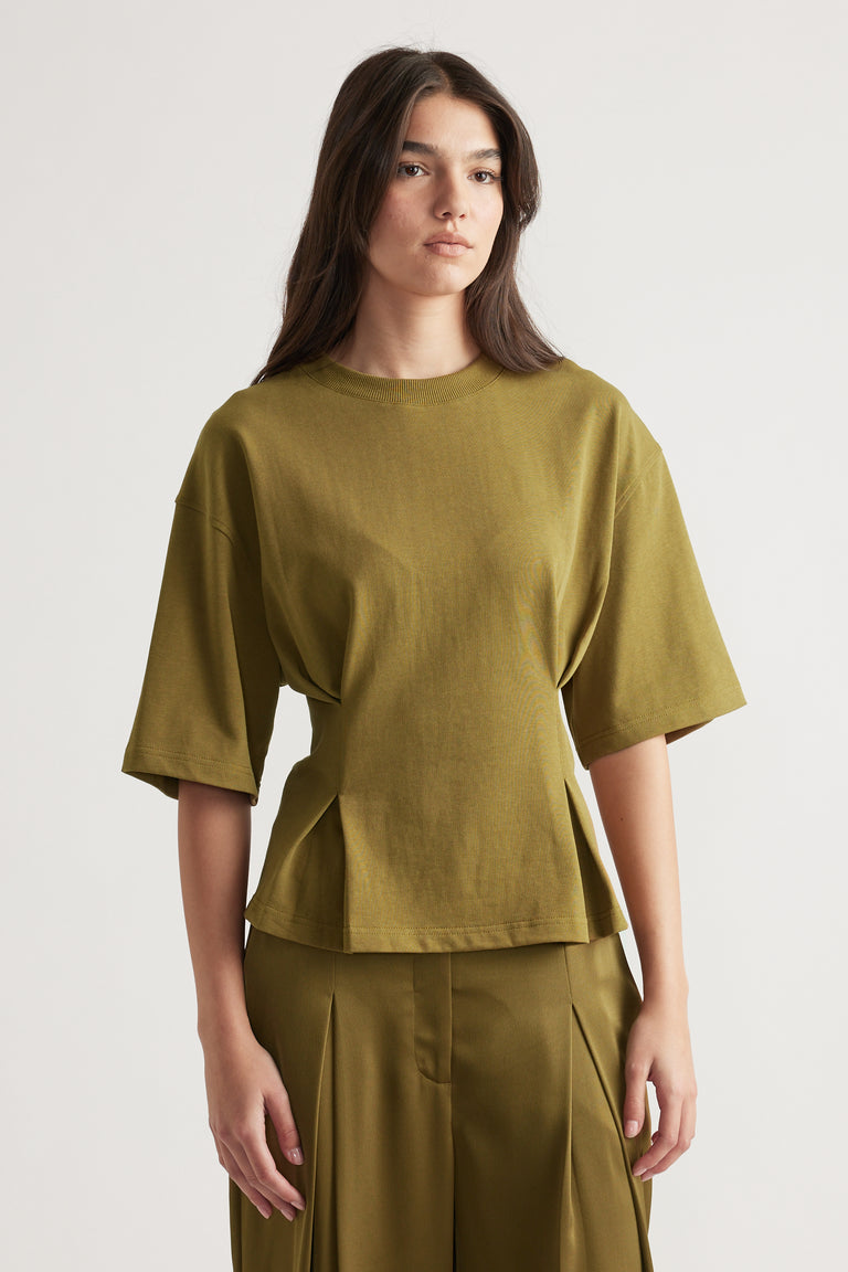 Woman wearing a structured olive green tee with wide sleeves paired with matching high-waisted pleated pants