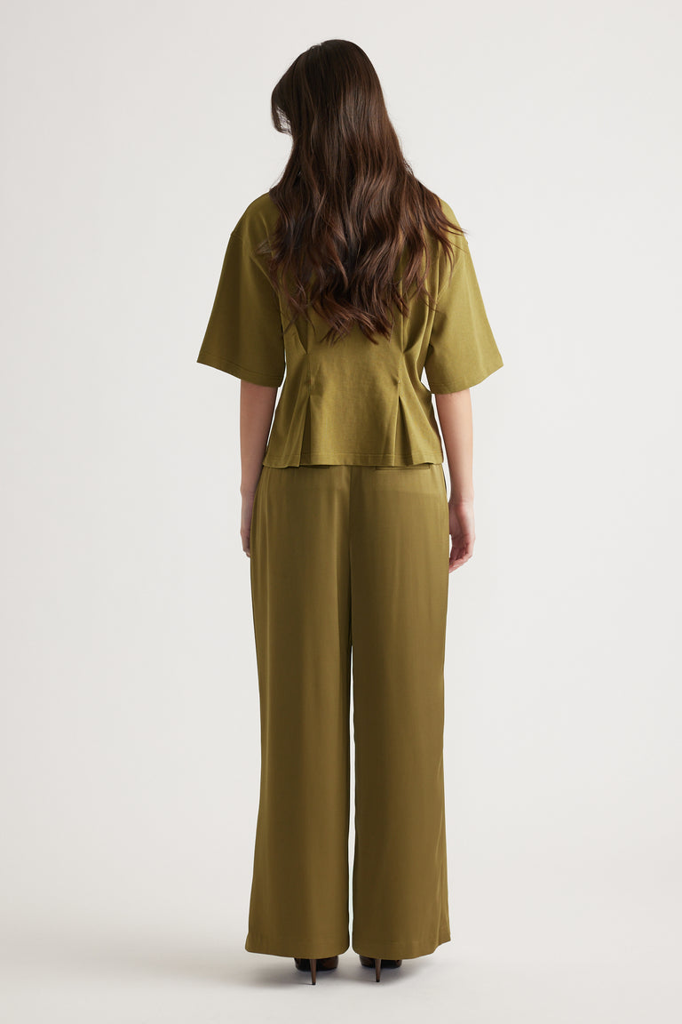 Woman shown from behind wearing an olive green structured top with wide sleeves and matching wide-leg pants
