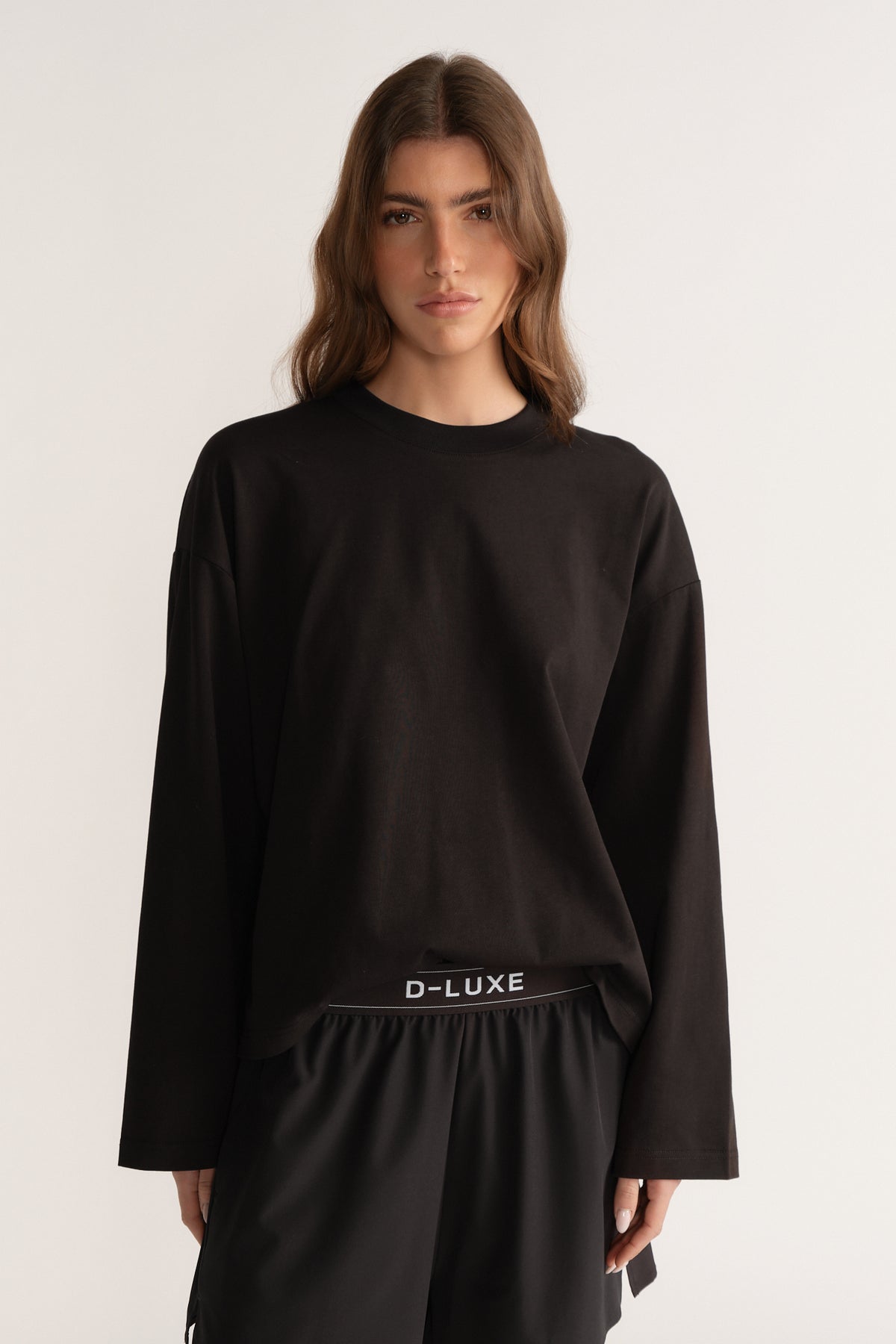 Model wearing a black oversized D-Luxe long sleeve tee with black drawstring pants