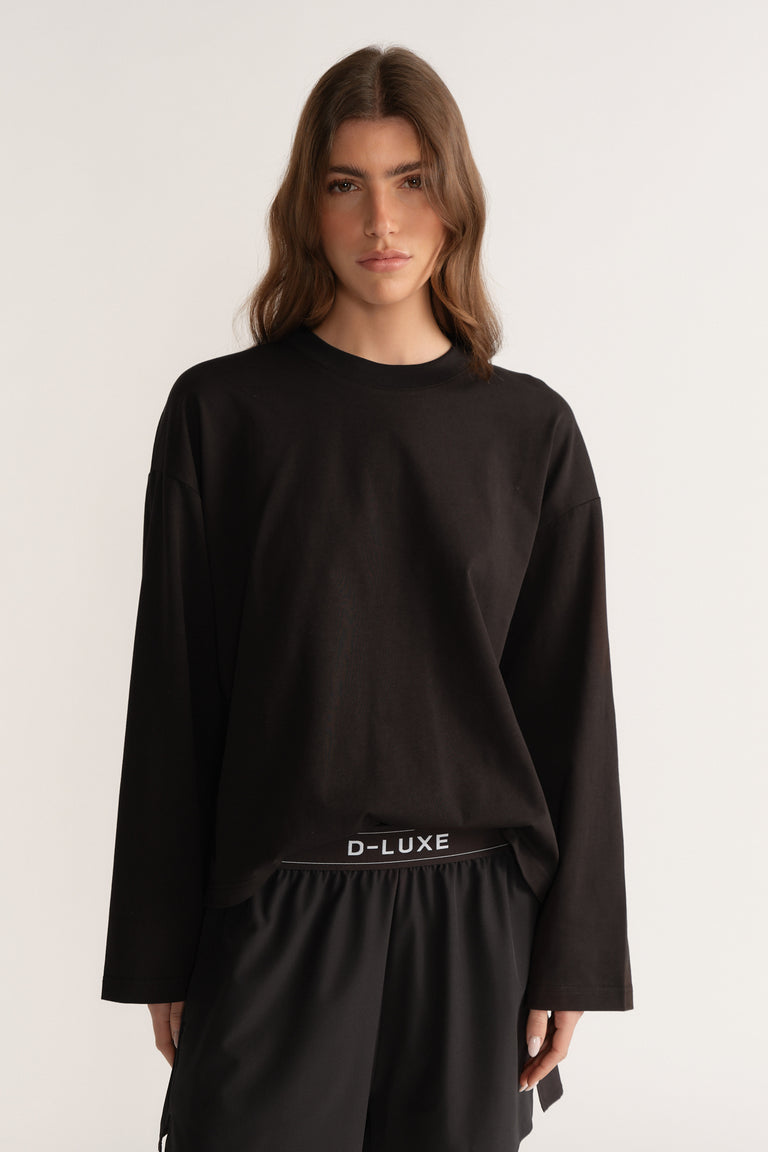 Model wearing a black oversized D-Luxe long sleeve tee with black drawstring pants