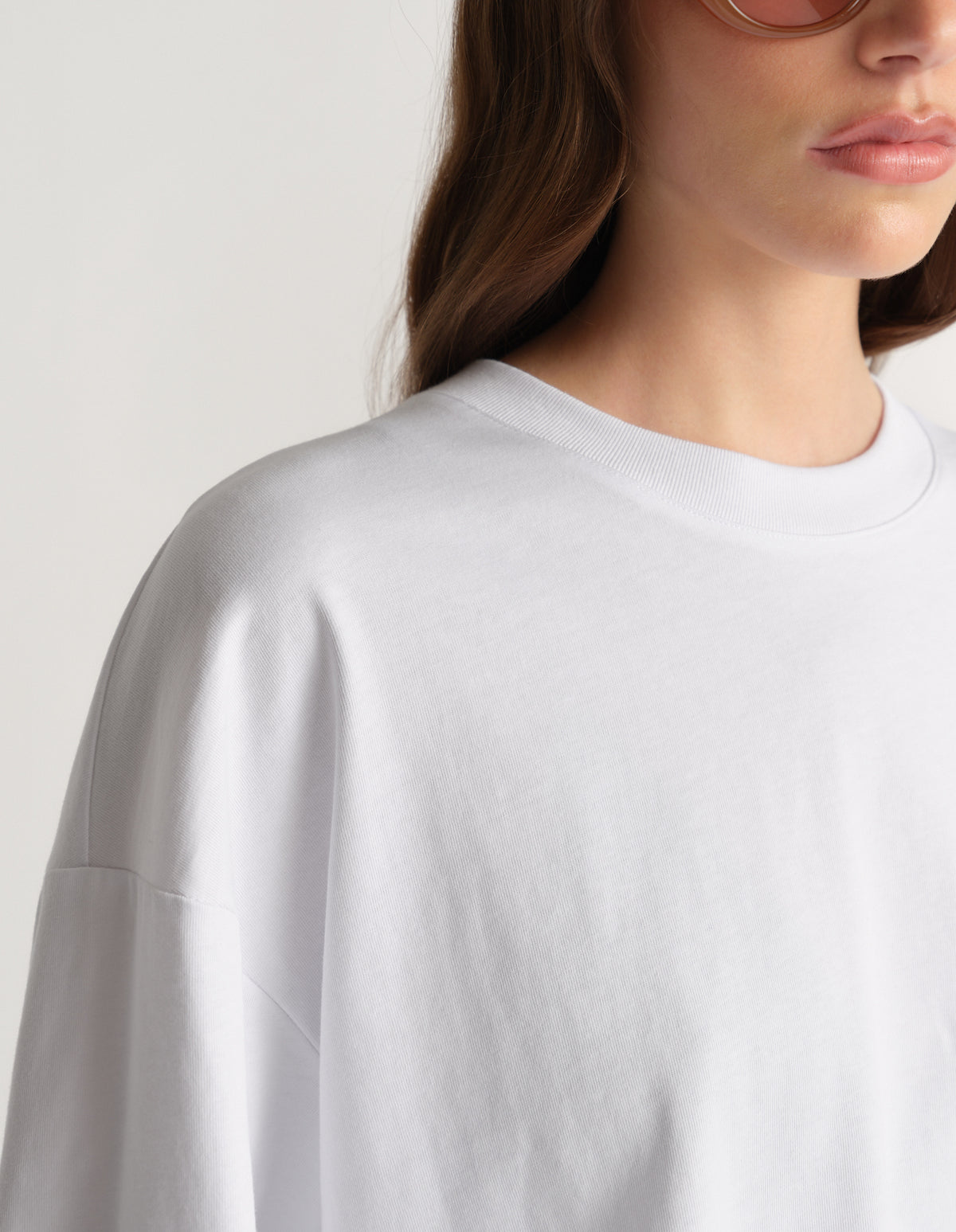 Woman wearing a white oversized long sleeve crew neck tee with drop shoulders