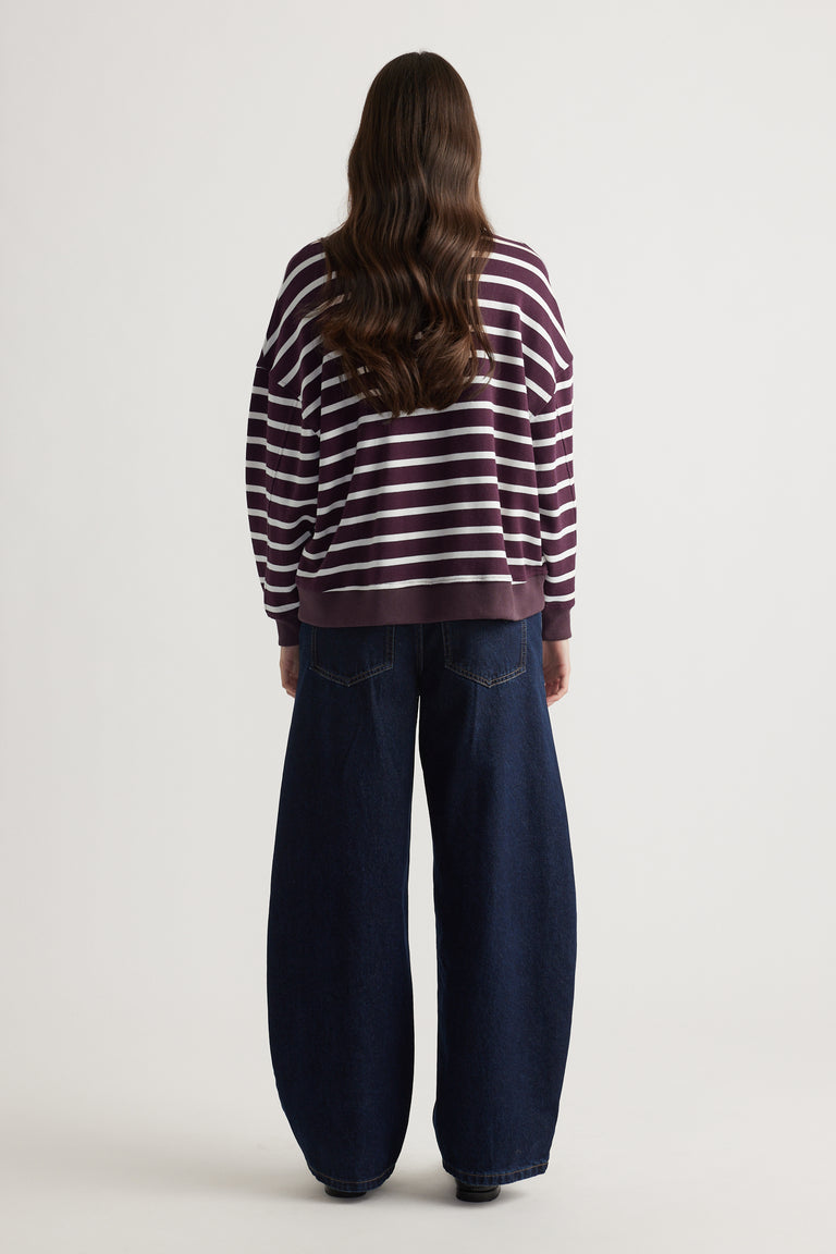 Woman wearing a relaxed striped burgundy and white sweatshirt paired with wide-leg dark denim jeans for a casual look