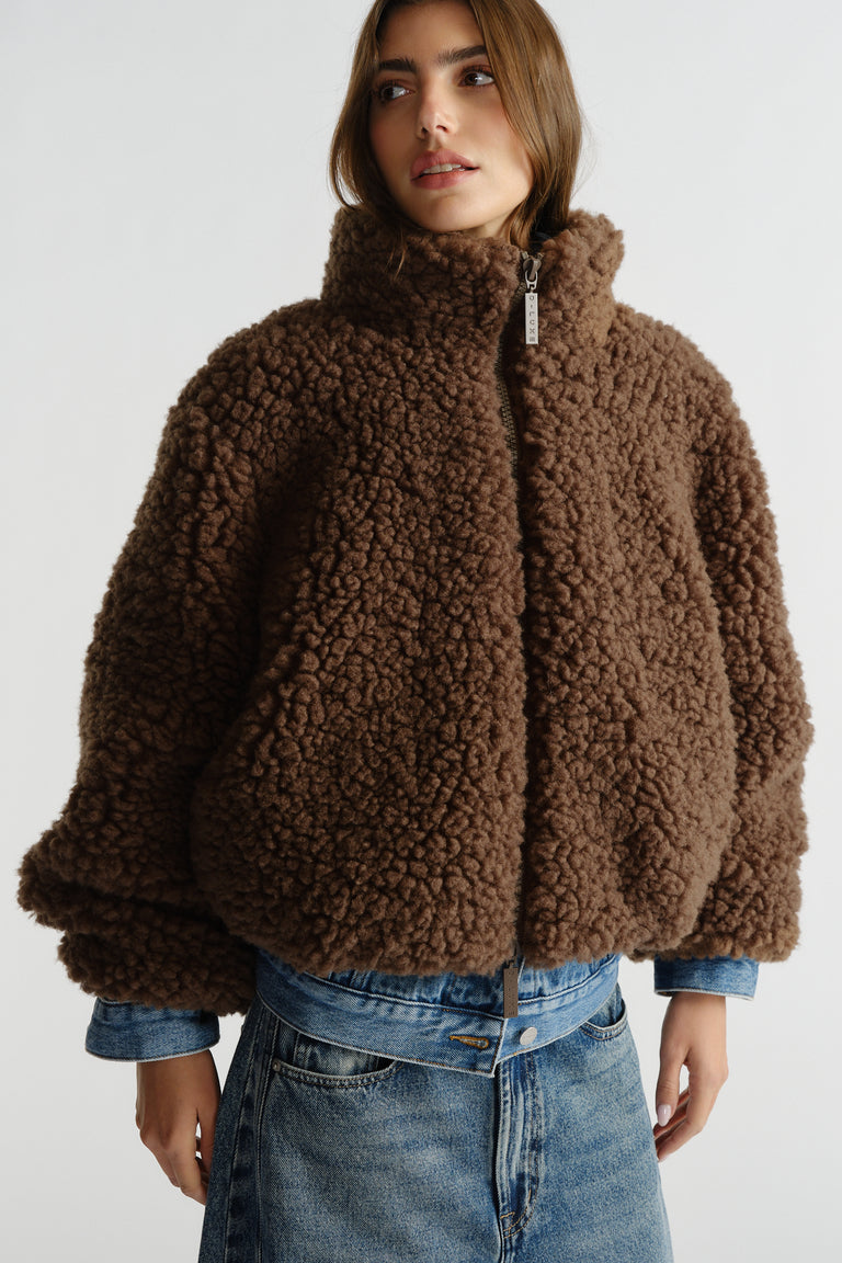 Brown textured sherpa bomber with high collar paired with light wash denim skirt for a cozy layered look