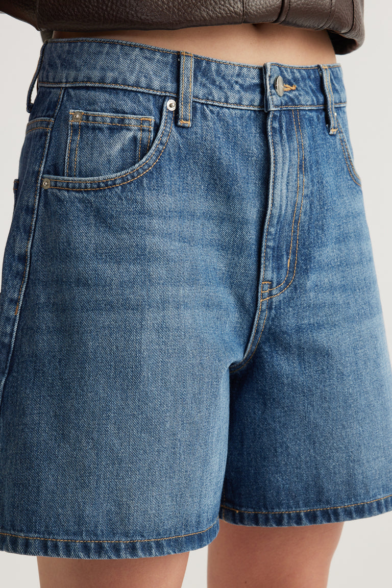 High rise blue A-line denim shorts with button and zip fly, front pockets and mid-thigh length