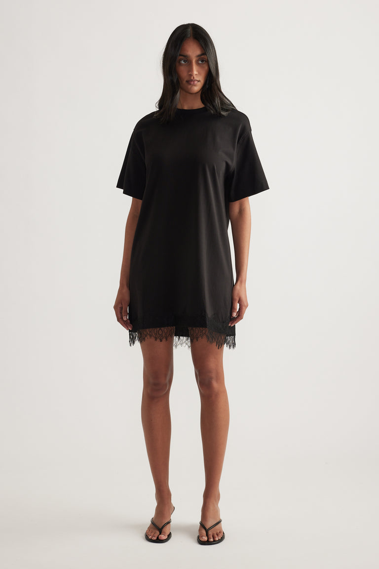 Woman wearing a black short sleeve mini dress with a crew neck and lace hem