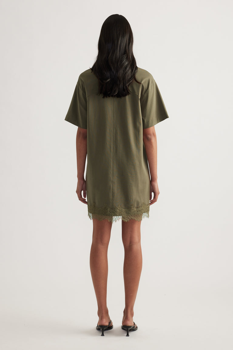 Back view of a woman wearing an olive green oversized tee dress with short sleeves and lace trim hem