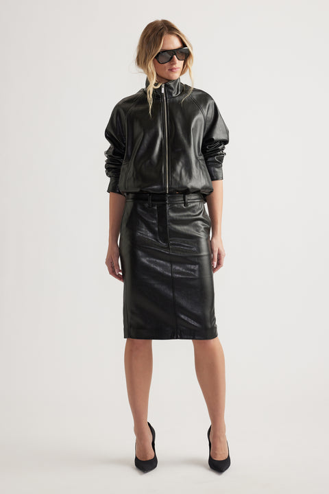 Woman wearing black zip-up faux leather jacket paired with high-waist straight faux leather pencil skirt and black heels