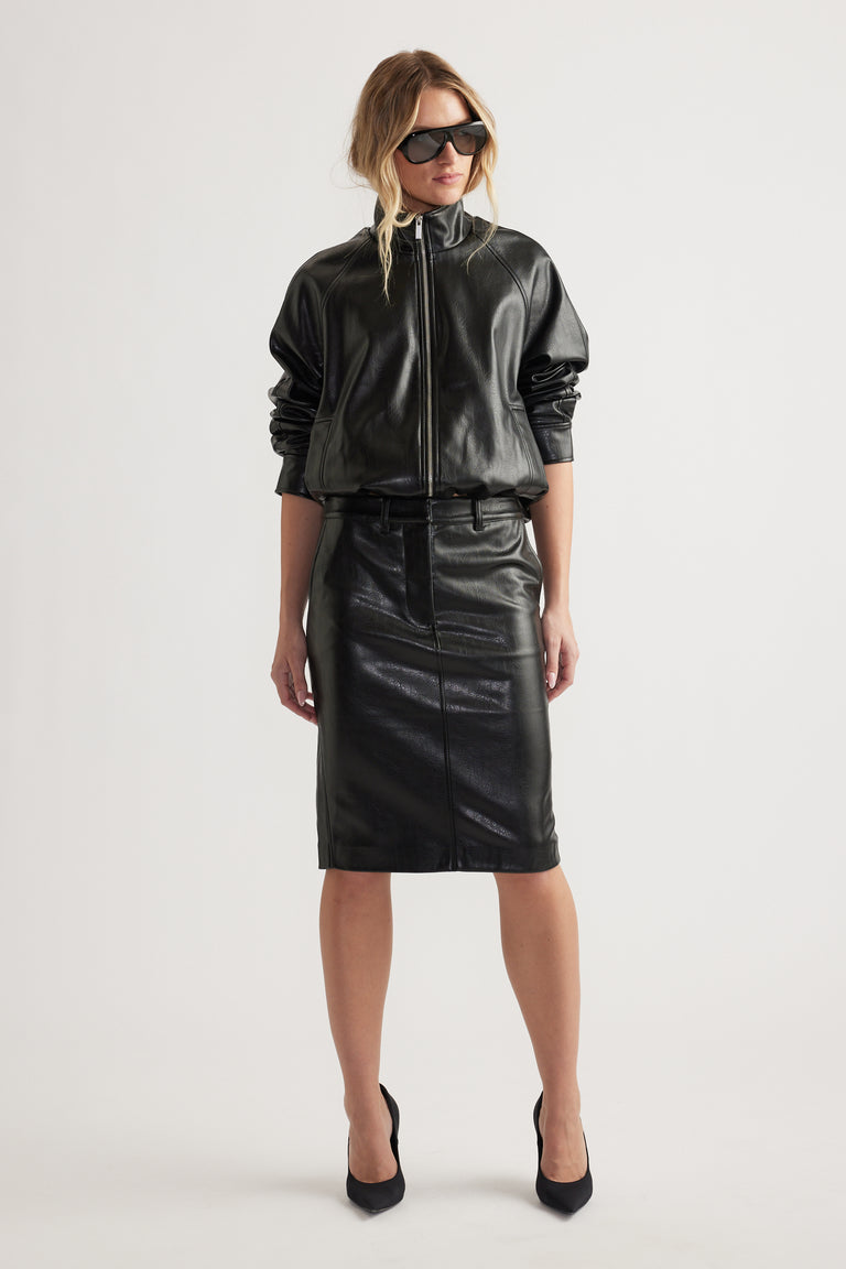 Woman wearing black zip-up faux leather jacket paired with high-waist straight faux leather pencil skirt and black heels