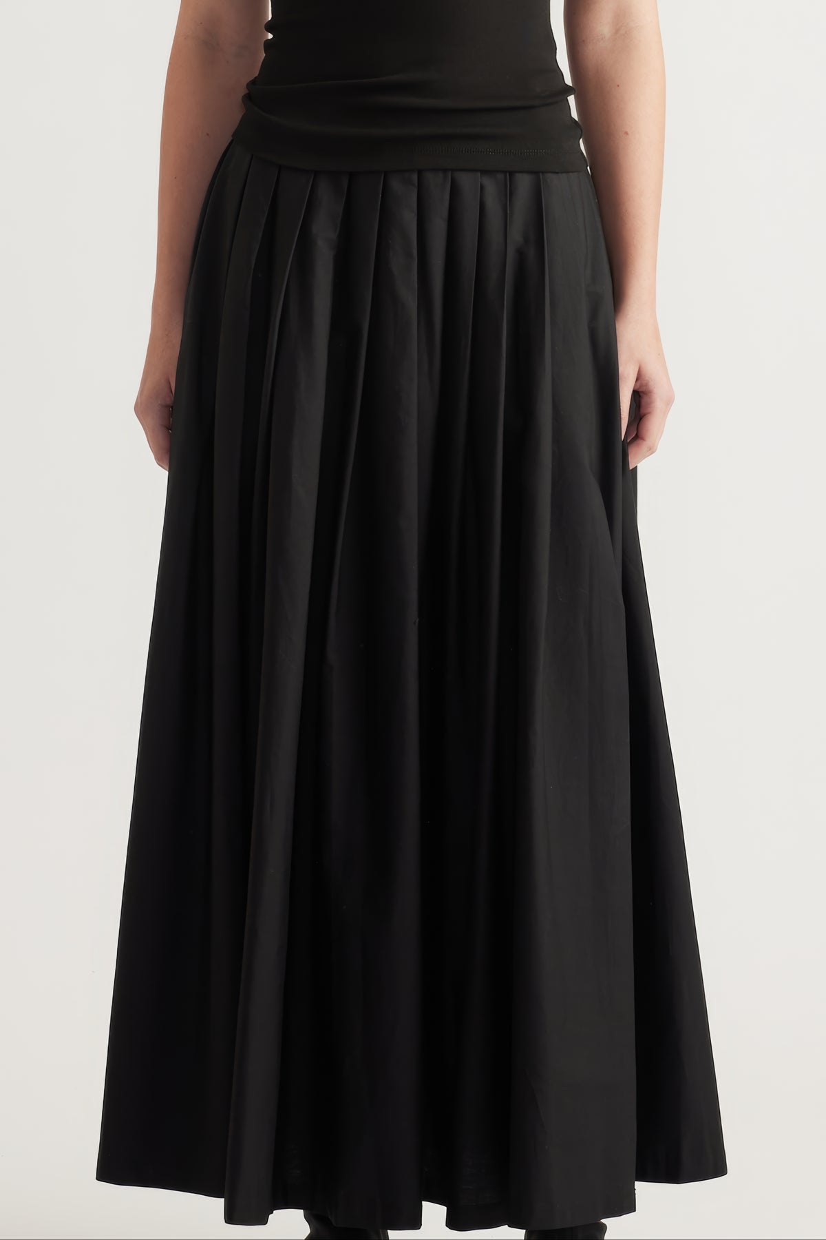 Black pleated ankle length A line skirt styled with a fitted top