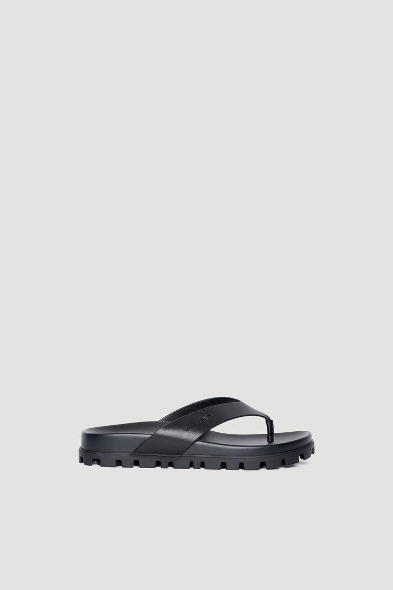 Black chunky platform thong sandal with slip-on design and textured anti-slip sole against plain background