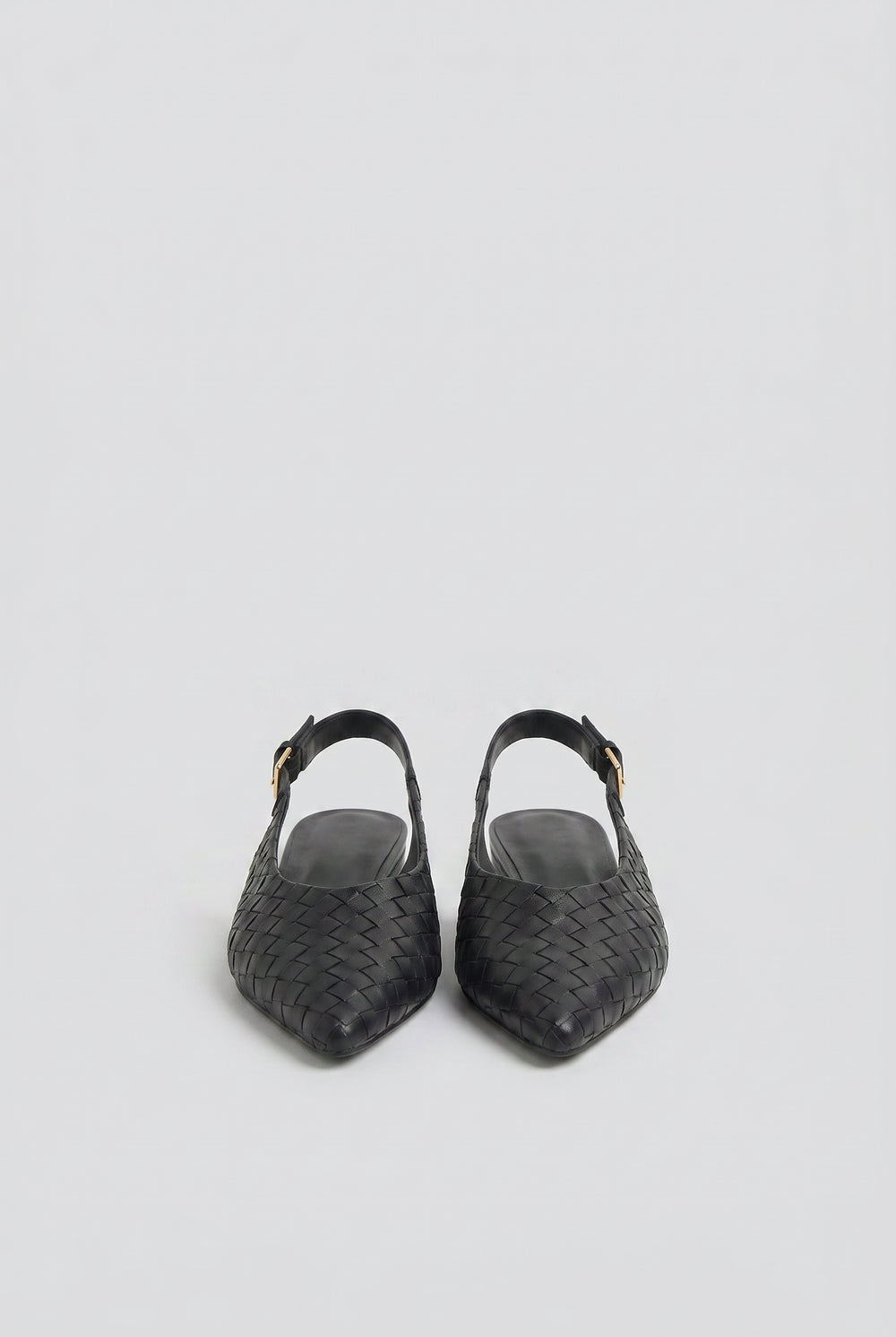Pair of black slingback flats with a woven leather design and adjustable gold buckle straps.