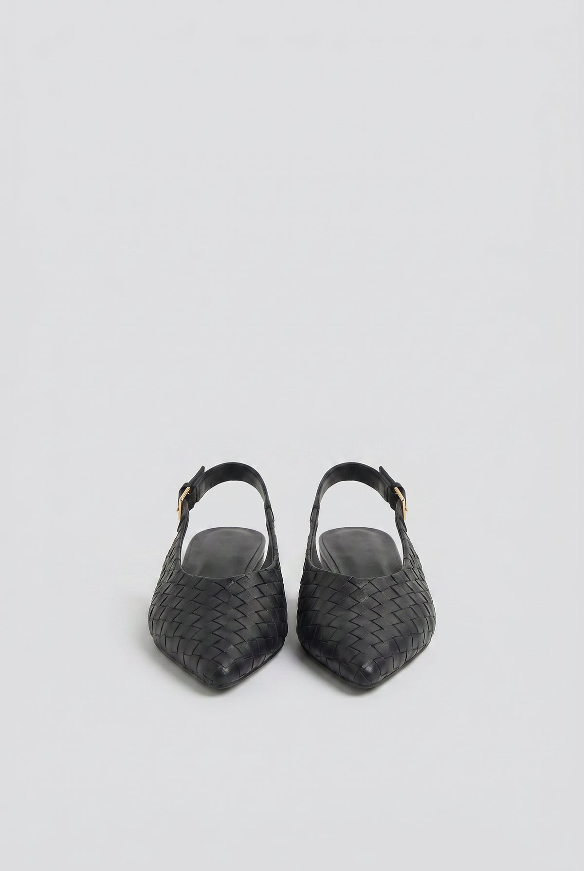 Pair of black slingback flats with a woven leather design and adjustable gold buckle straps.