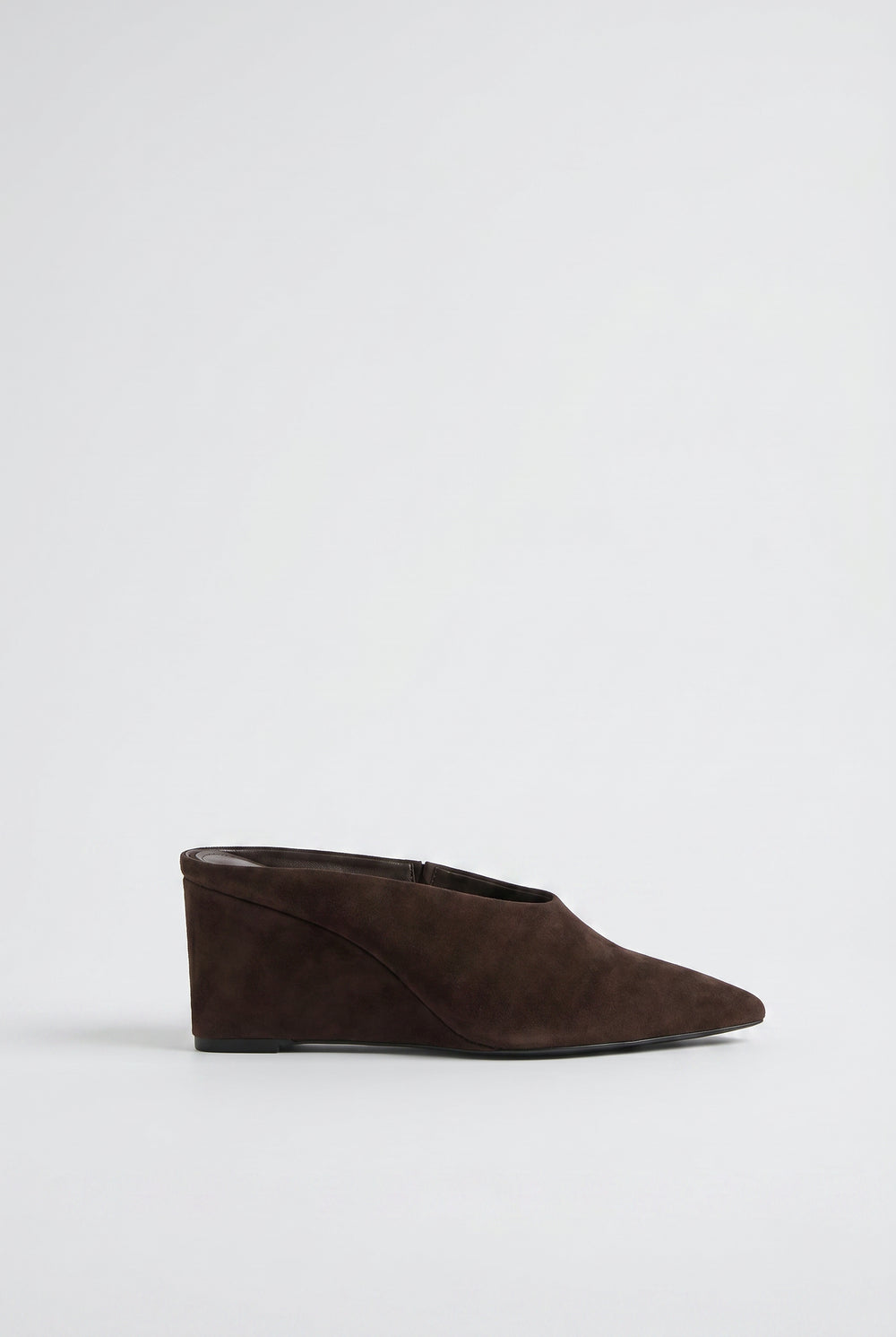 Side view of a sleek chocolate brown pointed wedge heel mule with smooth finish and clean lines.