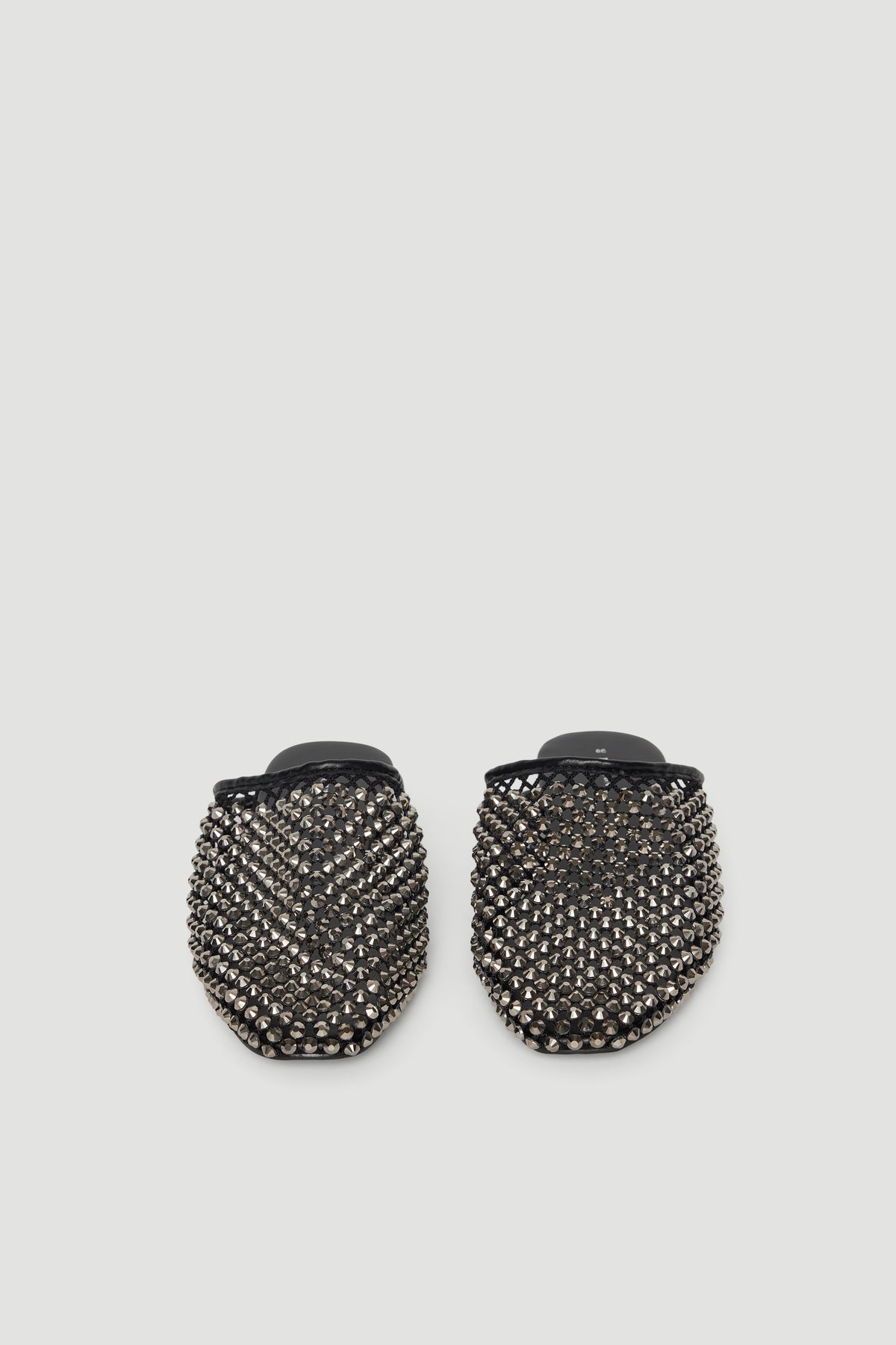 Black slip-on mules adorned with sparkling diamante studs for a bold, chic statement look.