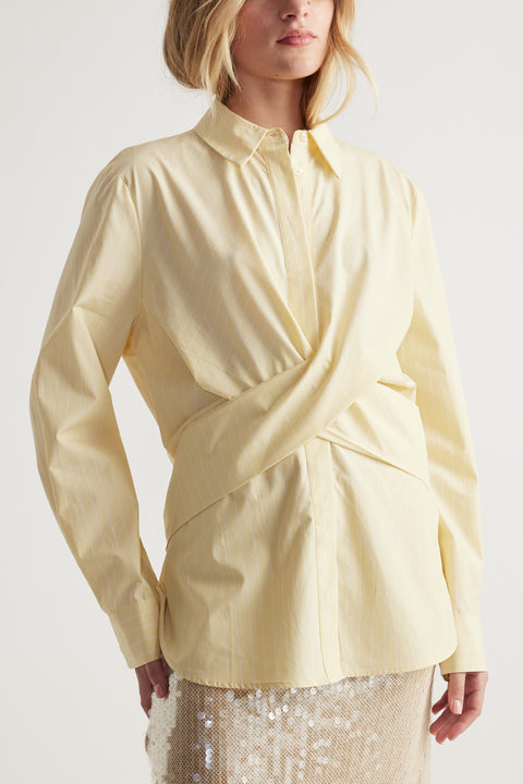 Woman wearing a soft yellow tie-front shirt with subtle stripes paired with a shimmering sequin skirt for an elegant look