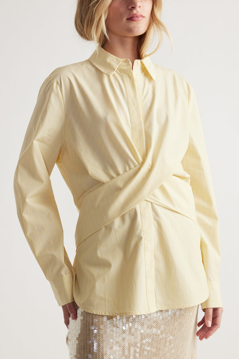 Woman wearing a soft yellow tie-front shirt with subtle stripes paired with a shimmering sequin skirt for an elegant look