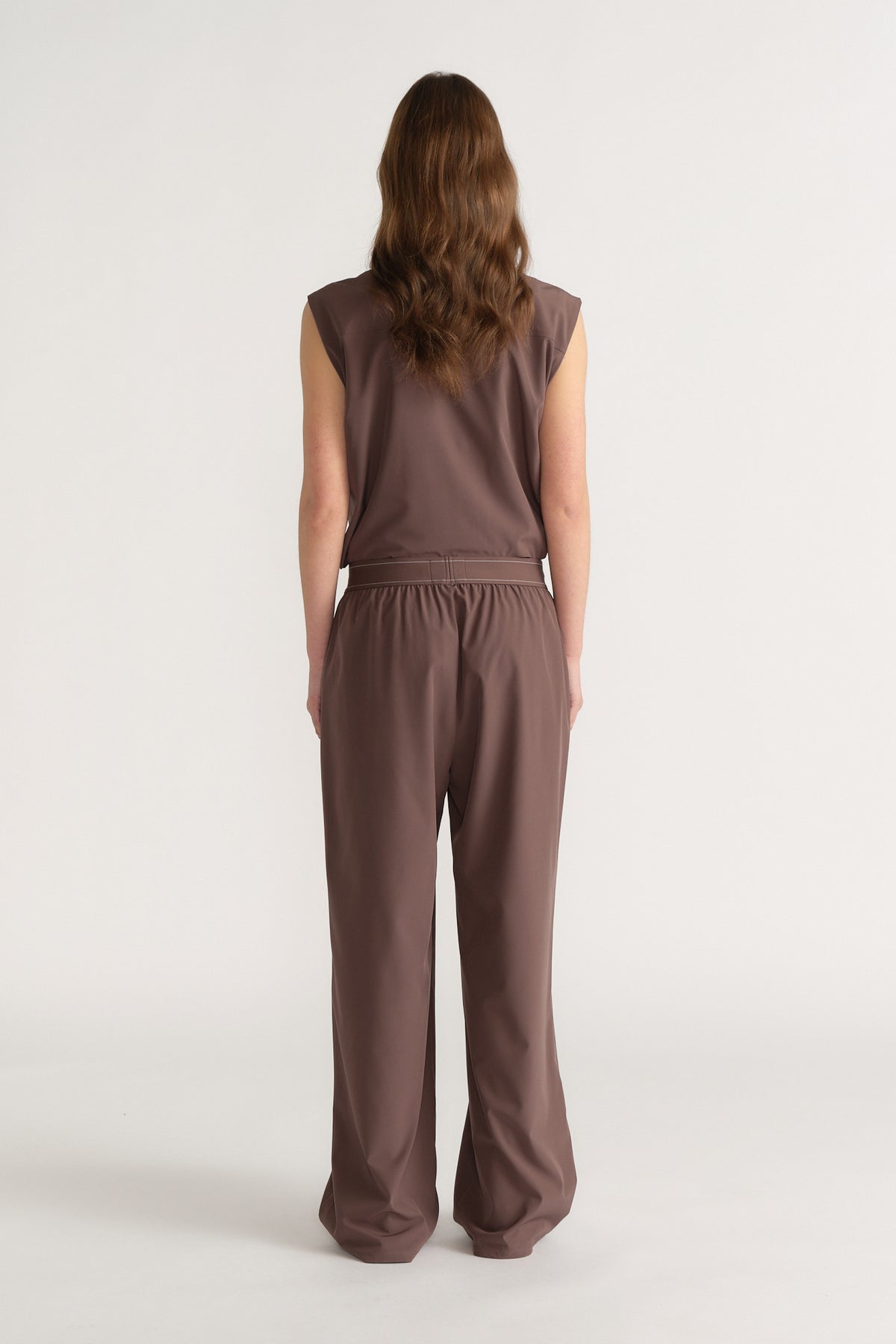 Back view of a woman wearing brown wide-leg pull-on pants with an elastic waist and matching sleeveless top