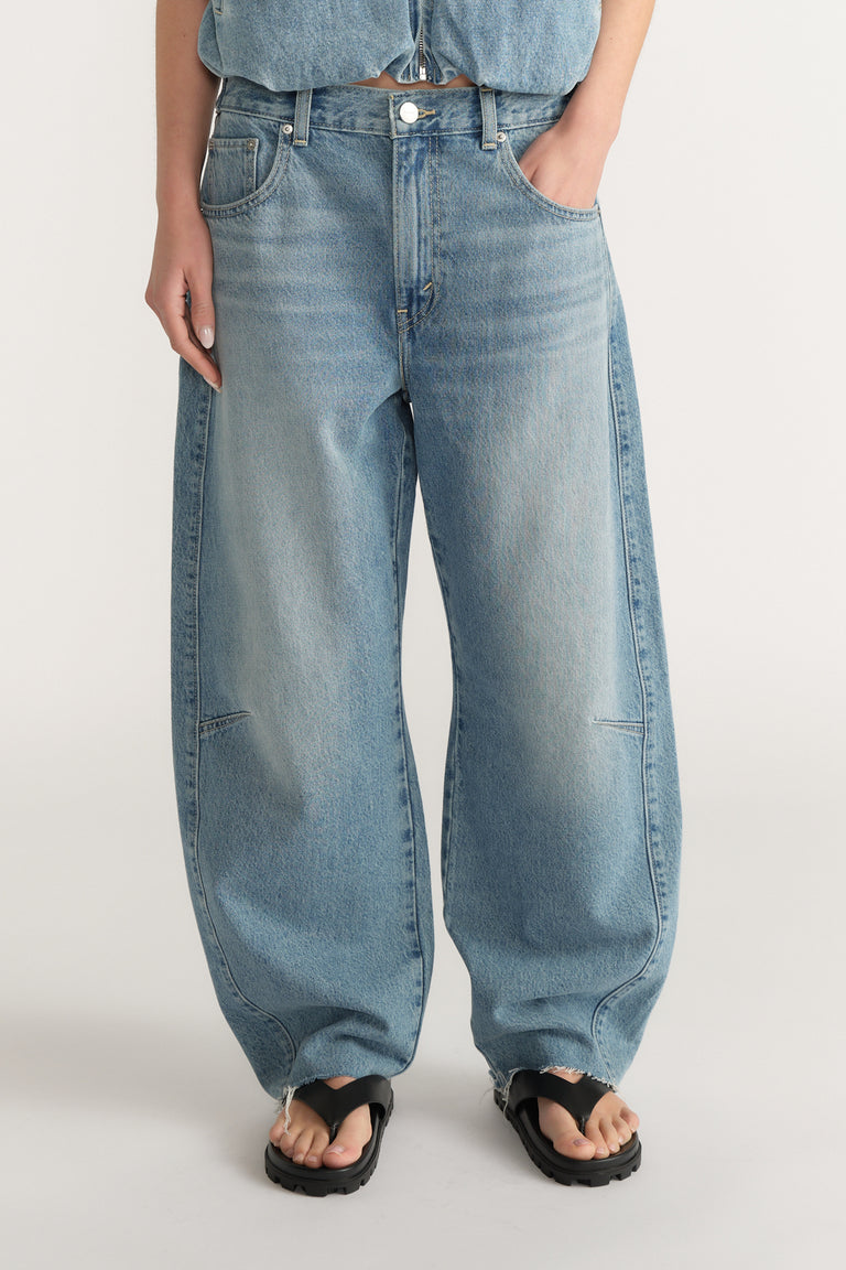 Front view of woman wearing light wash loose fit denim jeans with an adjustable waistband and black sandals