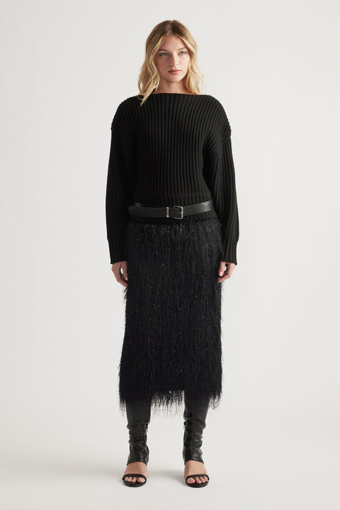 Woman wearing a black ribbed knit jumper with drop shoulders paired with a textured midi skirt and open-toe heels