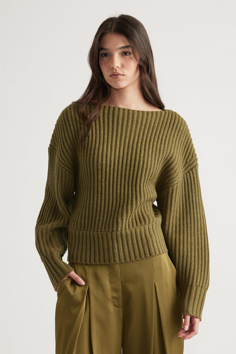 Woman wearing an olive green ribbed knit jumper with drop shoulder detail paired with matching high-waisted pants