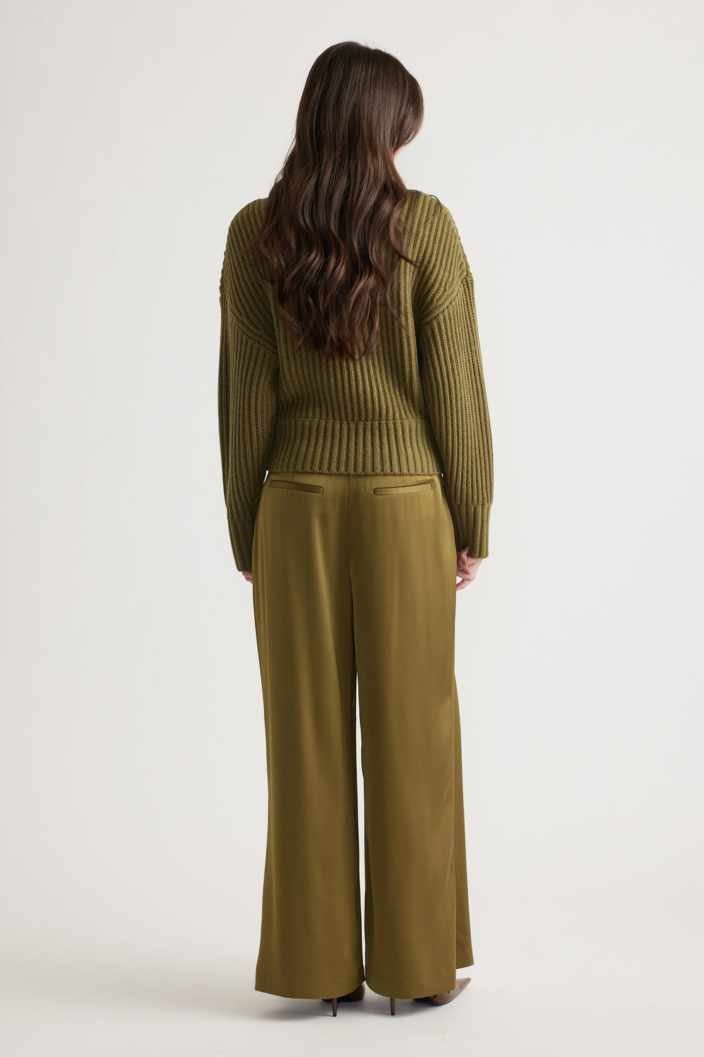 Back view of woman wearing an olive drop shoulder knit jumper paired with matching wide-leg trousers