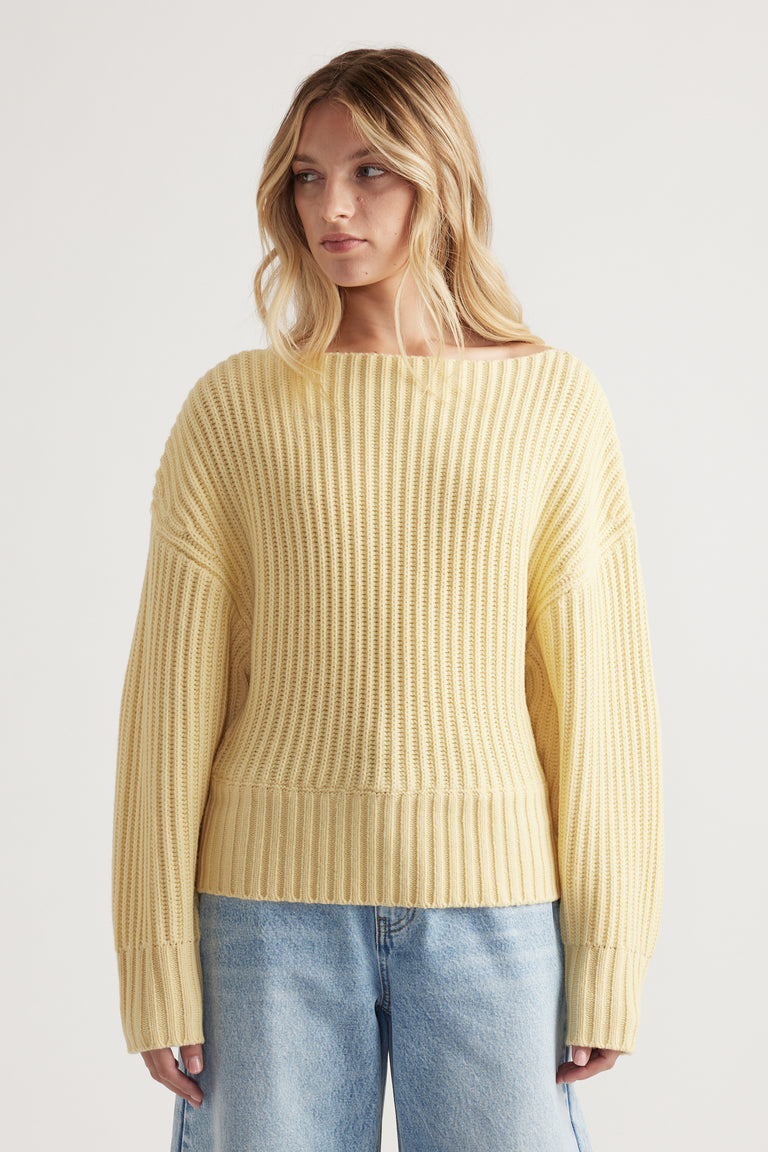 Woman wearing a soft yellow knit sweater with drop shoulders paired with relaxed light blue denim jeans