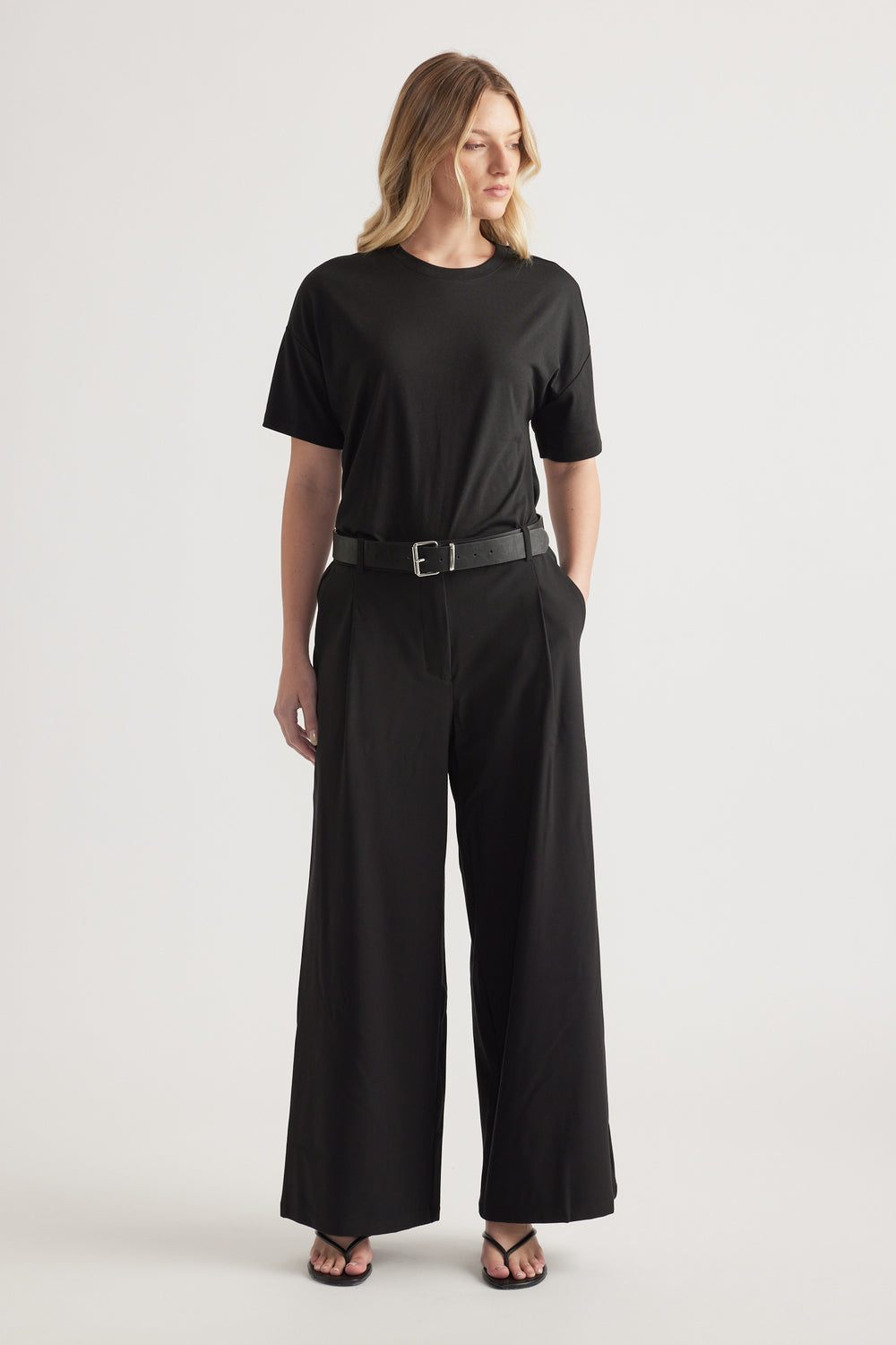Woman wearing black high-rise wide-leg pants with a belt and relaxed black tee outfit