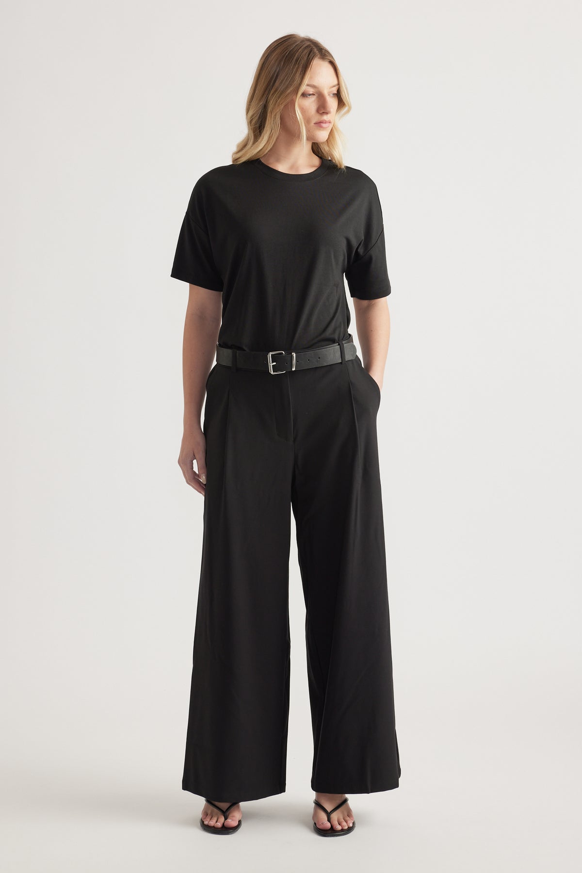 Woman wearing black high-rise wide-leg pants with a belt and relaxed black tee outfit