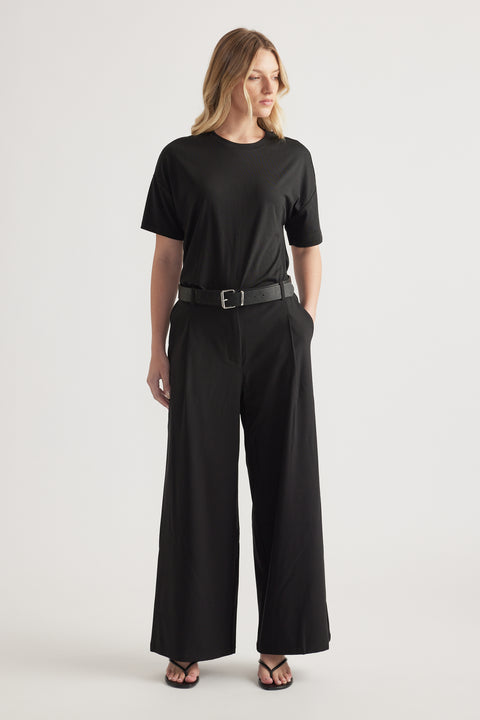 Woman wearing black high-rise wide-leg pants with a belt and relaxed black tee outfit