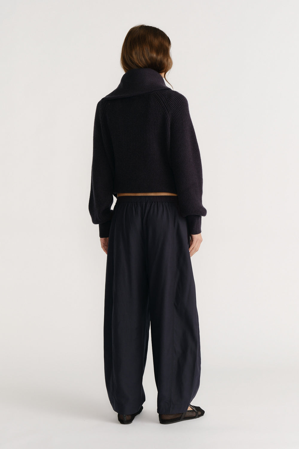 Woman wearing relaxed navy pants with an elastic waist and a cropped dark knit sweater, styled for casual comfort.