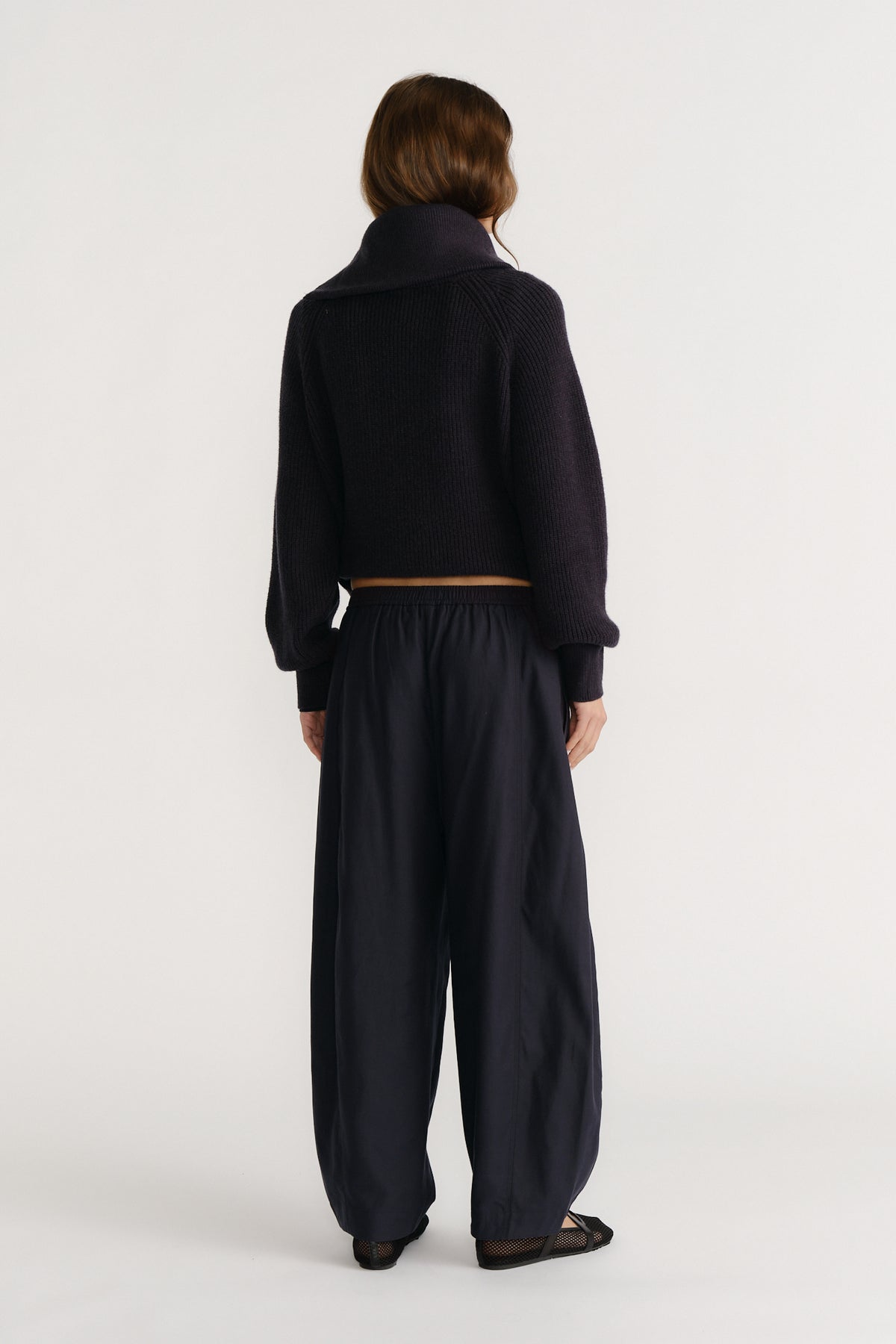 Woman wearing relaxed navy pants with an elastic waist and a cropped dark knit sweater, styled for casual comfort.