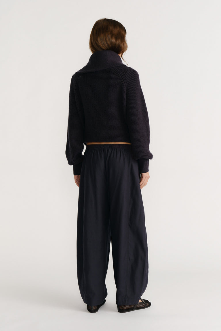 Woman wearing relaxed navy pants with an elastic waist and a cropped dark knit sweater, styled for casual comfort.