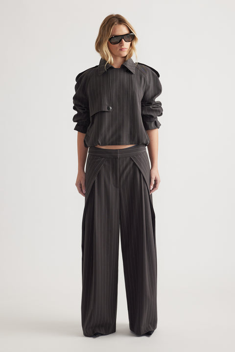 Woman wearing high rise wide leg pinstripe pants with pleat details and a cropped matching jacket and sunglasses