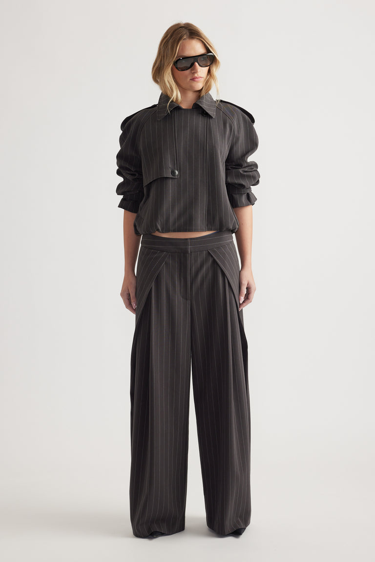 Woman wearing high rise wide leg pinstripe pants with pleat details and a cropped matching jacket and sunglasses