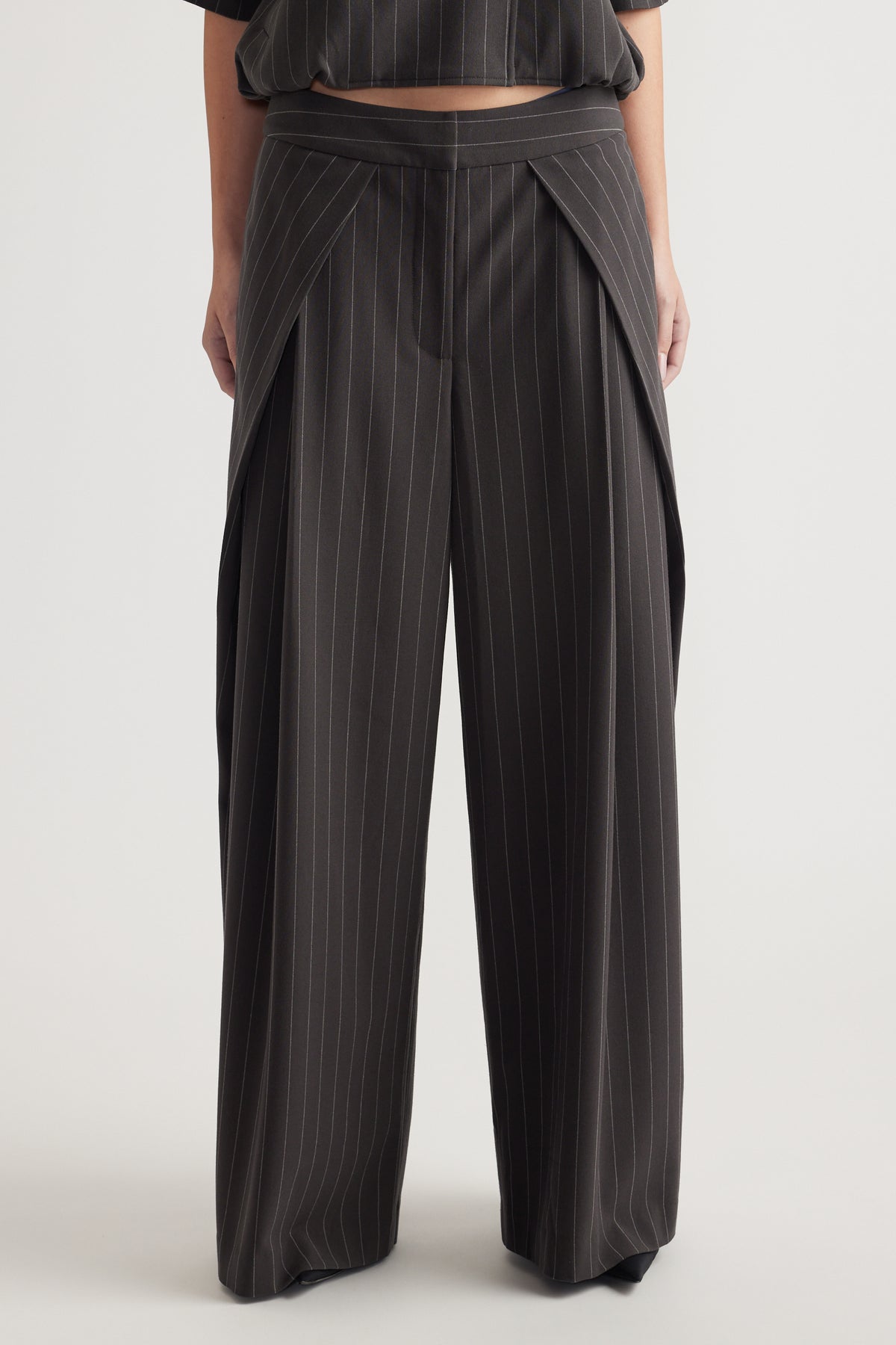 Front view of high-rise wide leg pinstripe pants with pleat details and soft drape on the model