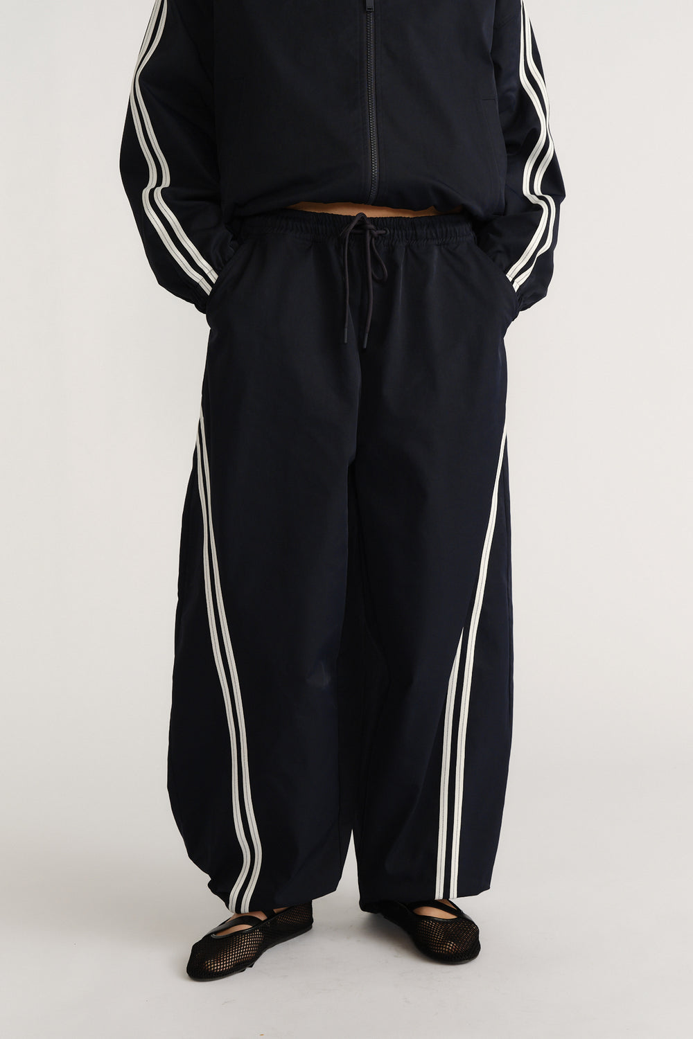 Navy relaxed fit barrel pants with white side stripes and an elastic drawstring waist for a sporty casual style