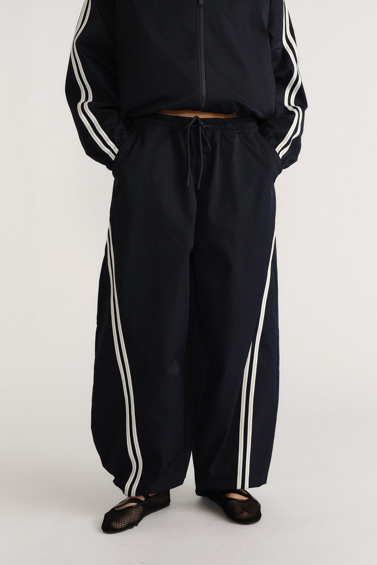 Navy relaxed fit barrel pants with white side stripes and an elastic drawstring waist for a sporty casual style