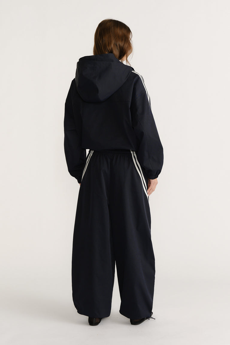 Woman viewed from behind wearing a navy hooded jacket and matching wide-leg pants with white side stripes for a casual look
