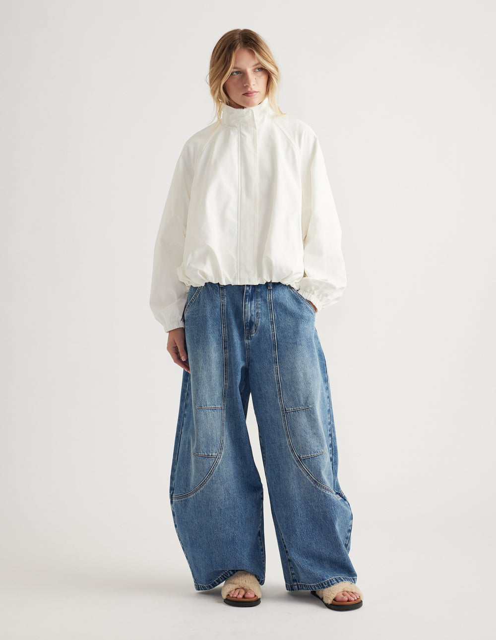 Woman wearing oversized light denim wide-leg jeans with seam details and a loose white zip-up jacket