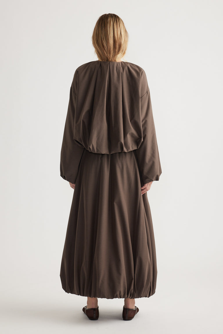 Woman wearing a loose, dark brown bubble midi skirt paired with a matching oversized top in a relaxed silhouette.