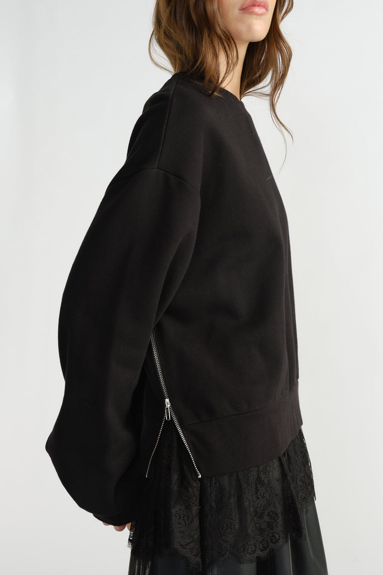 Black sweatshirt with side zipper detail and delicate lace trim peeking from the hem for a stylish layered effect.