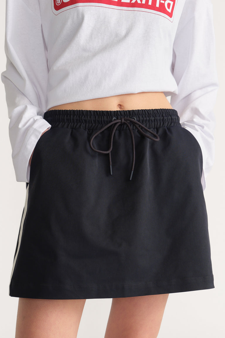 Woman wearing a black mini skirt with an elastic drawstring waist and white side stripe