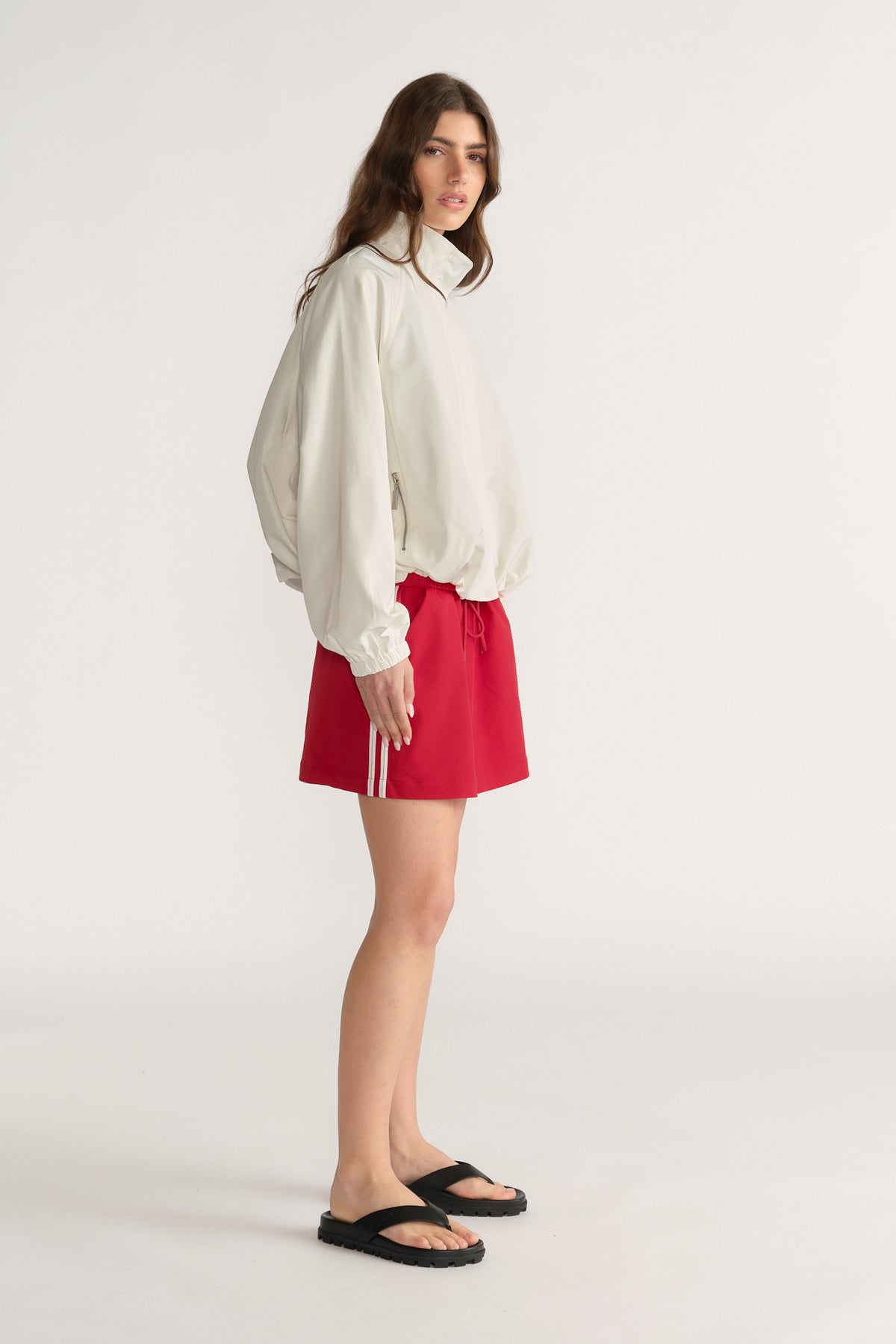 Woman wearing a white blouse with a red side stripe mini skirt and black sandals