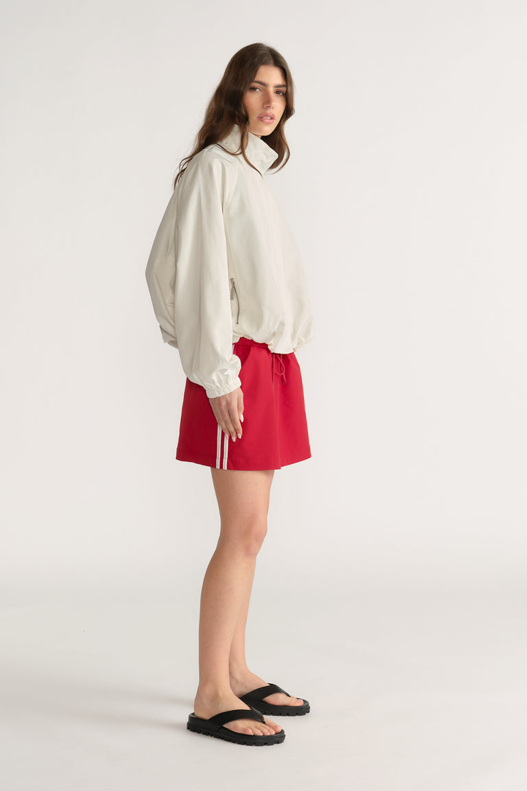 Woman wearing a white blouse with a red side stripe mini skirt and black sandals