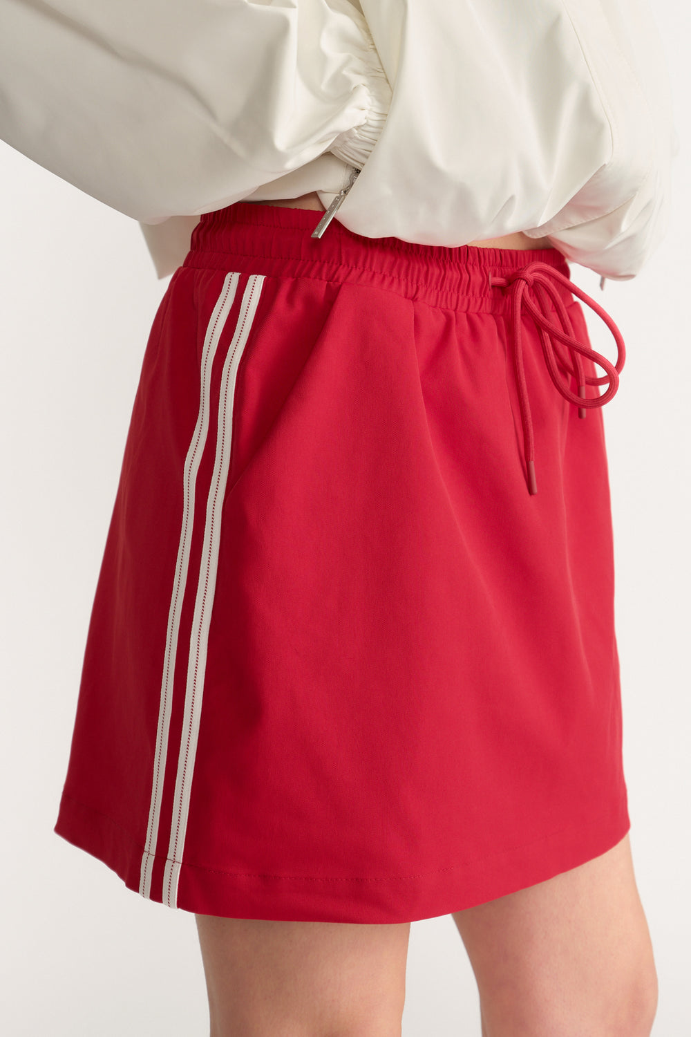 Woman wearing a red mini skirt with an elastic drawstring waist and double white side stripes